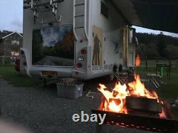 Foyer de feu de camp en plein air avec grille pour barbecue et brûleur de bûches, sièges extérieurs, spectacle de feu, camping.